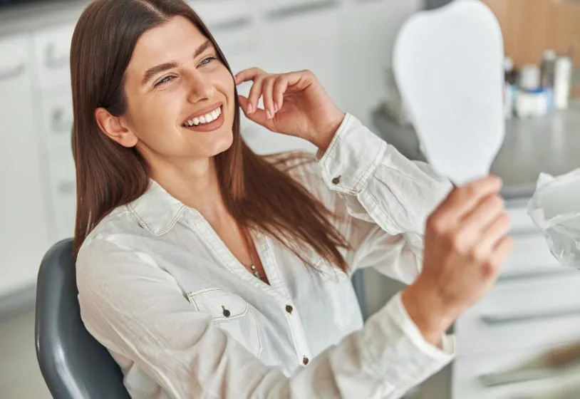 woman looking at her smile in the mirror at New Life Dental in Germantown, MD